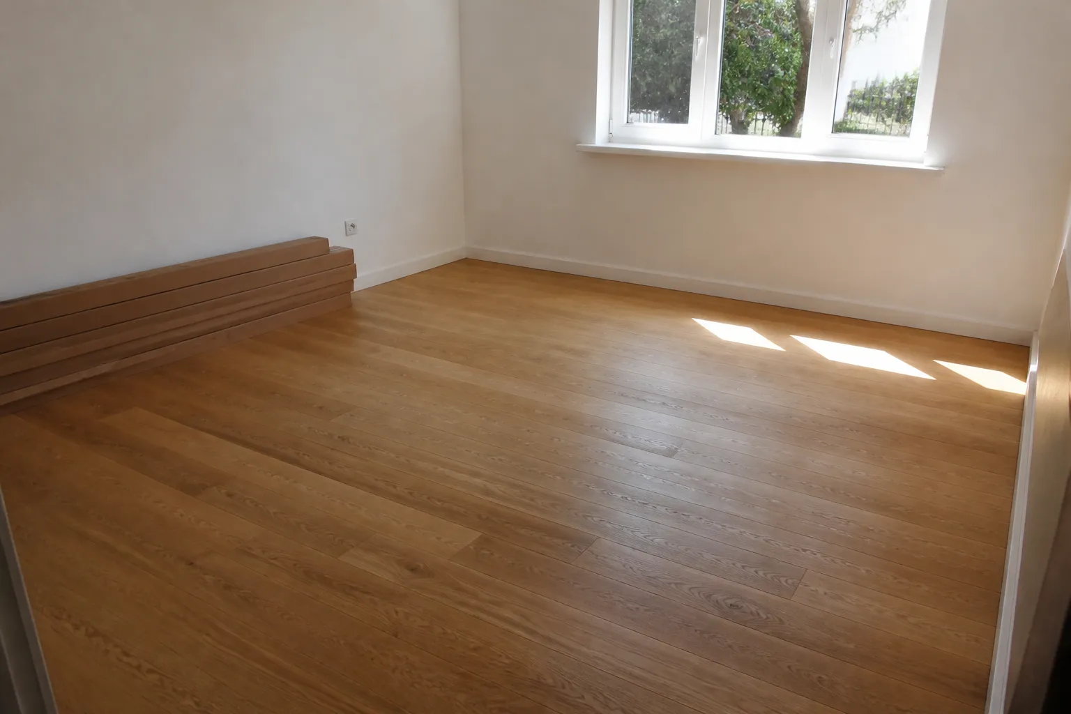 Lege gerenoveerde woonkamer met een nieuw afgewerkte eiken vloer en een groot raam